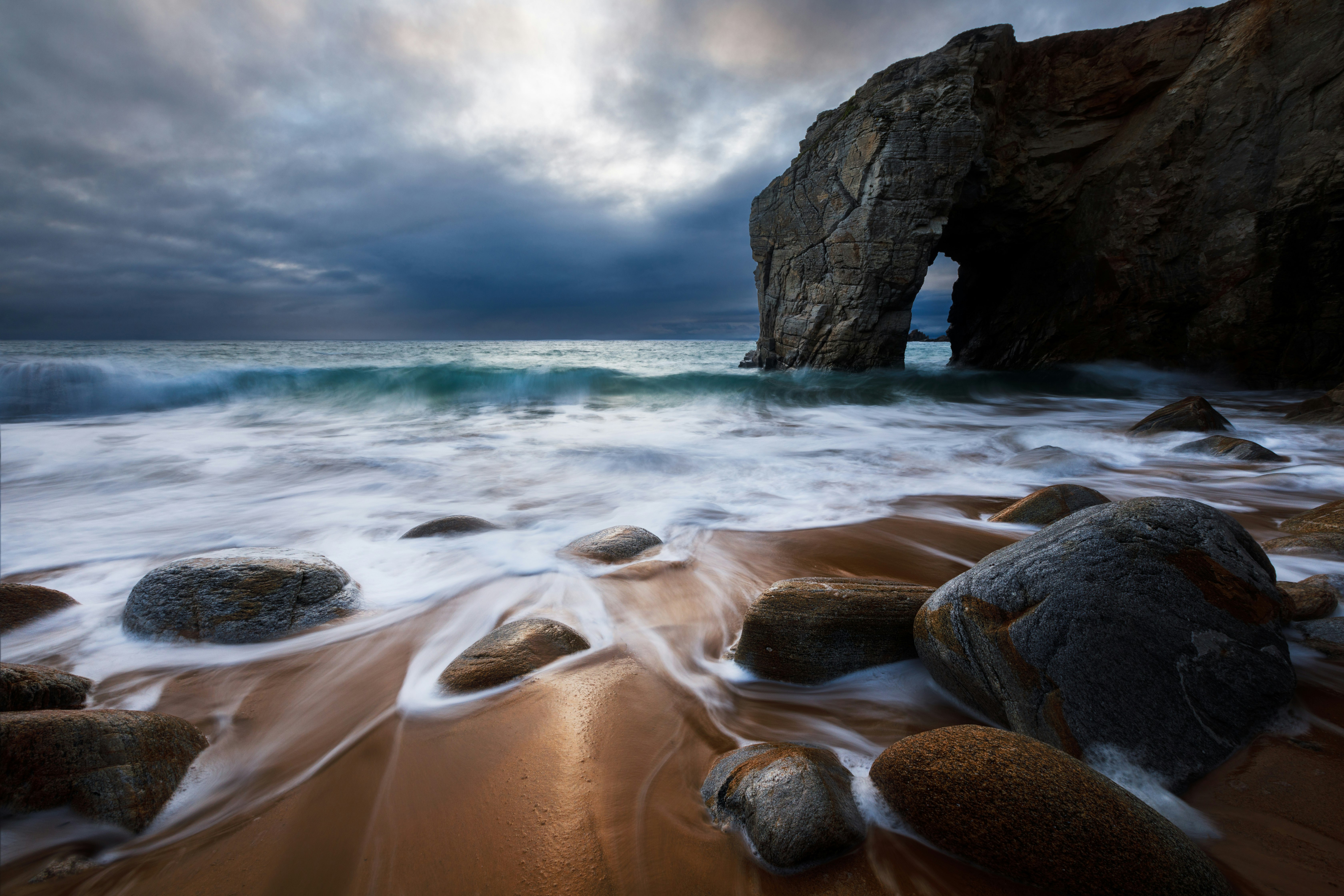 brown rock formation on sea water under white clouds during daytime